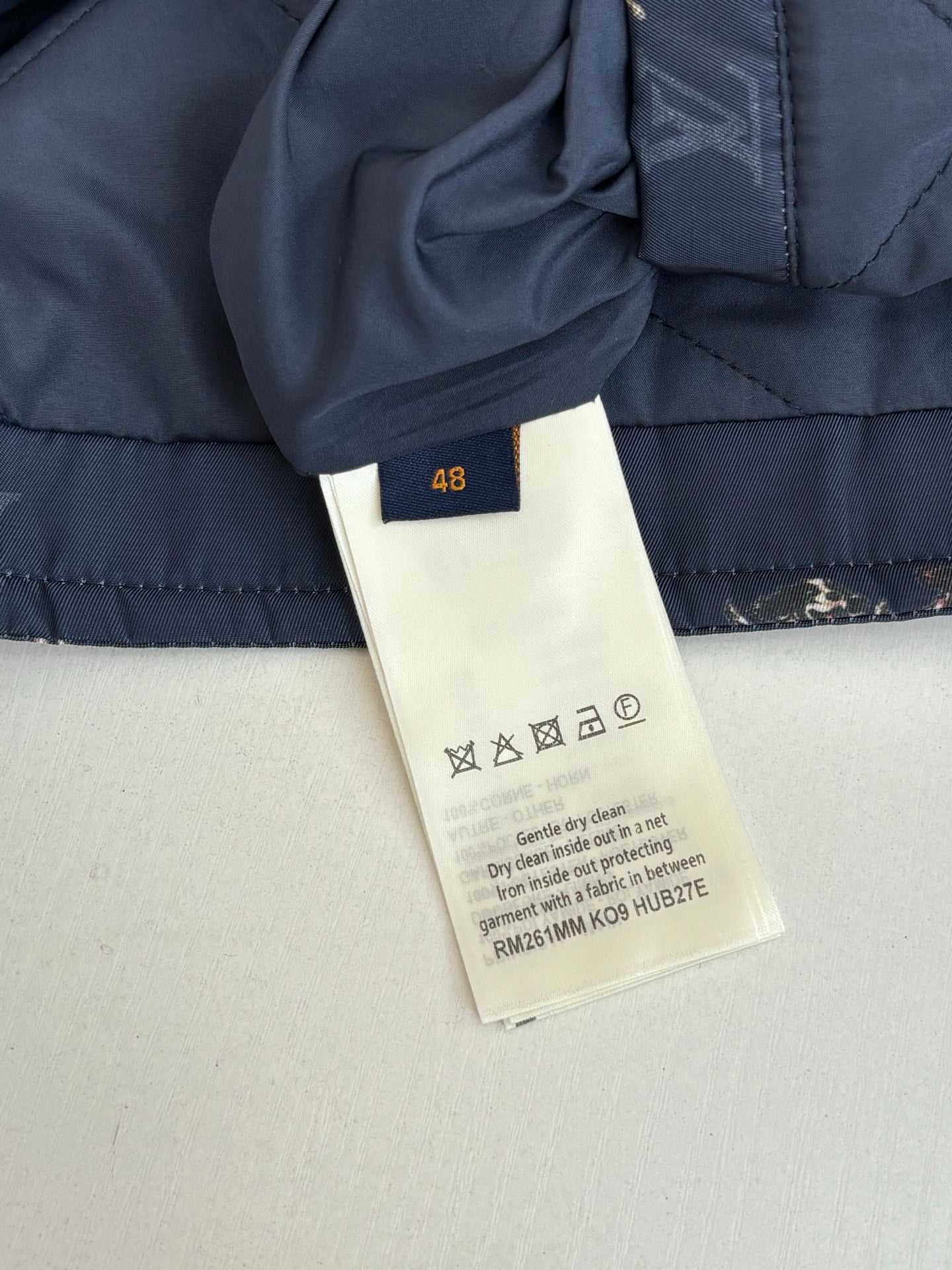 Louis Vuitton long quilted jacket care label and size tag on navy fabric