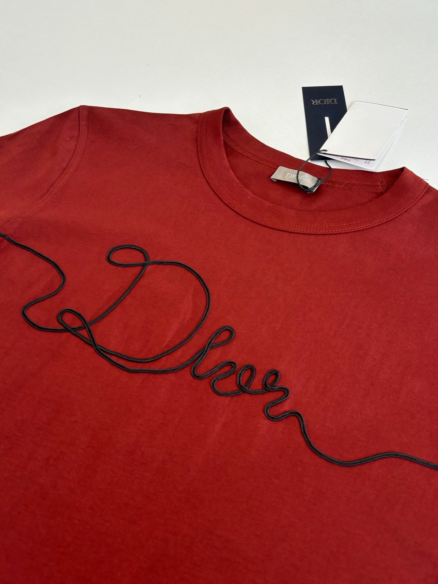 Dior red T-shirt with large black cursive logo on chest