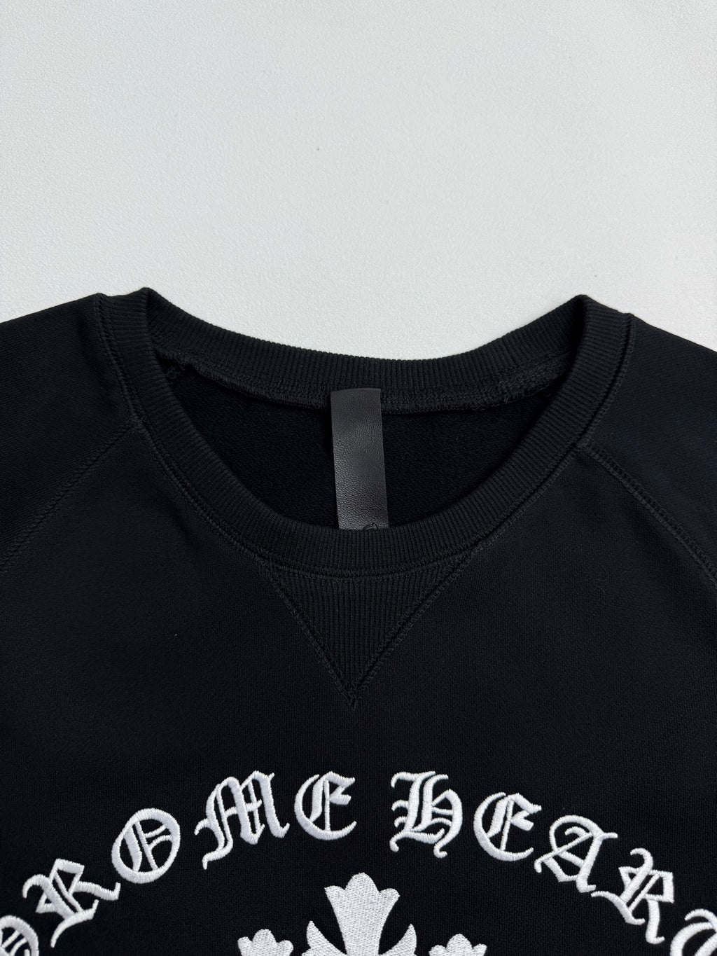 Black crewneck sweatshirt with white logo print near the neckline