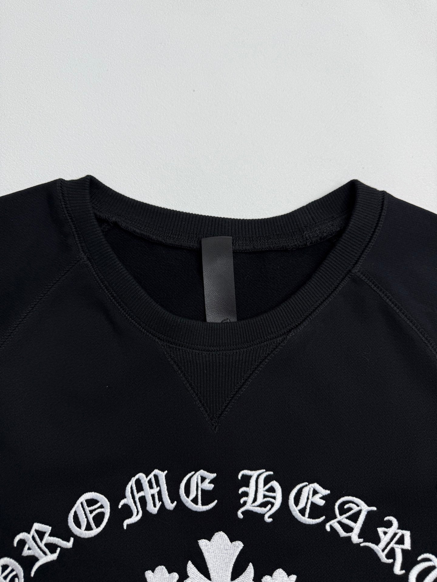 Black crewneck sweatshirt with white logo print near the neckline