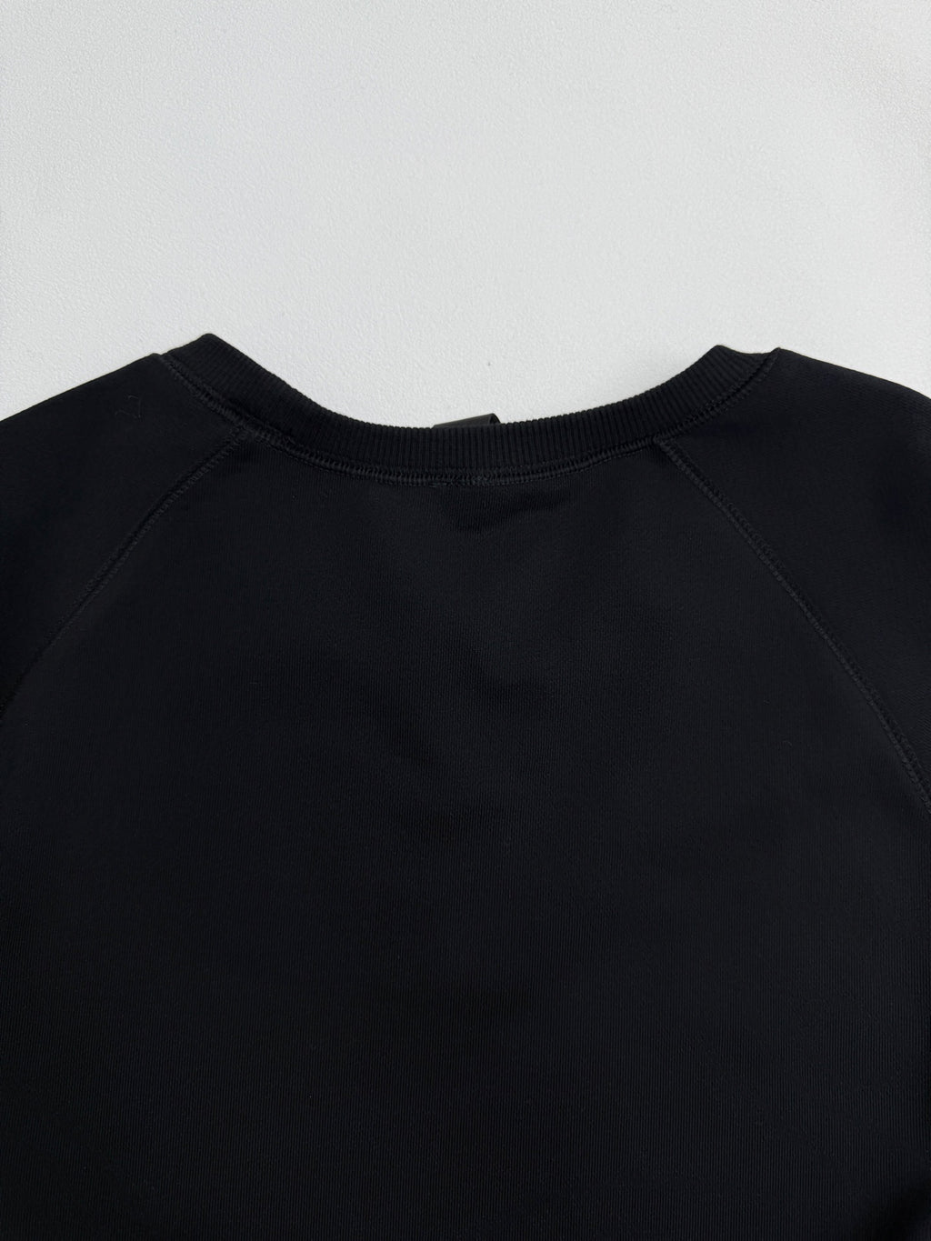Black raglan-style crewneck sweatshirt with smooth neckline seam