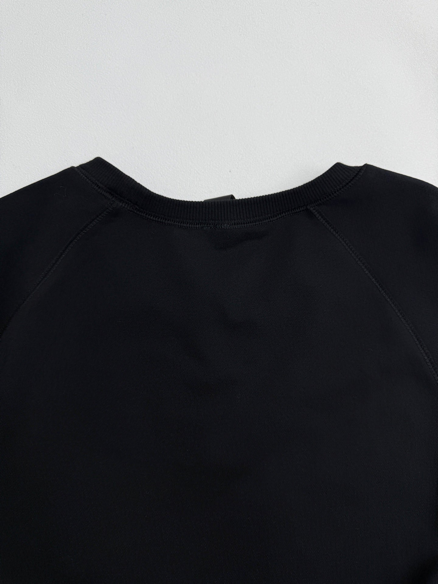 Black raglan-style crewneck sweatshirt with smooth neckline seam