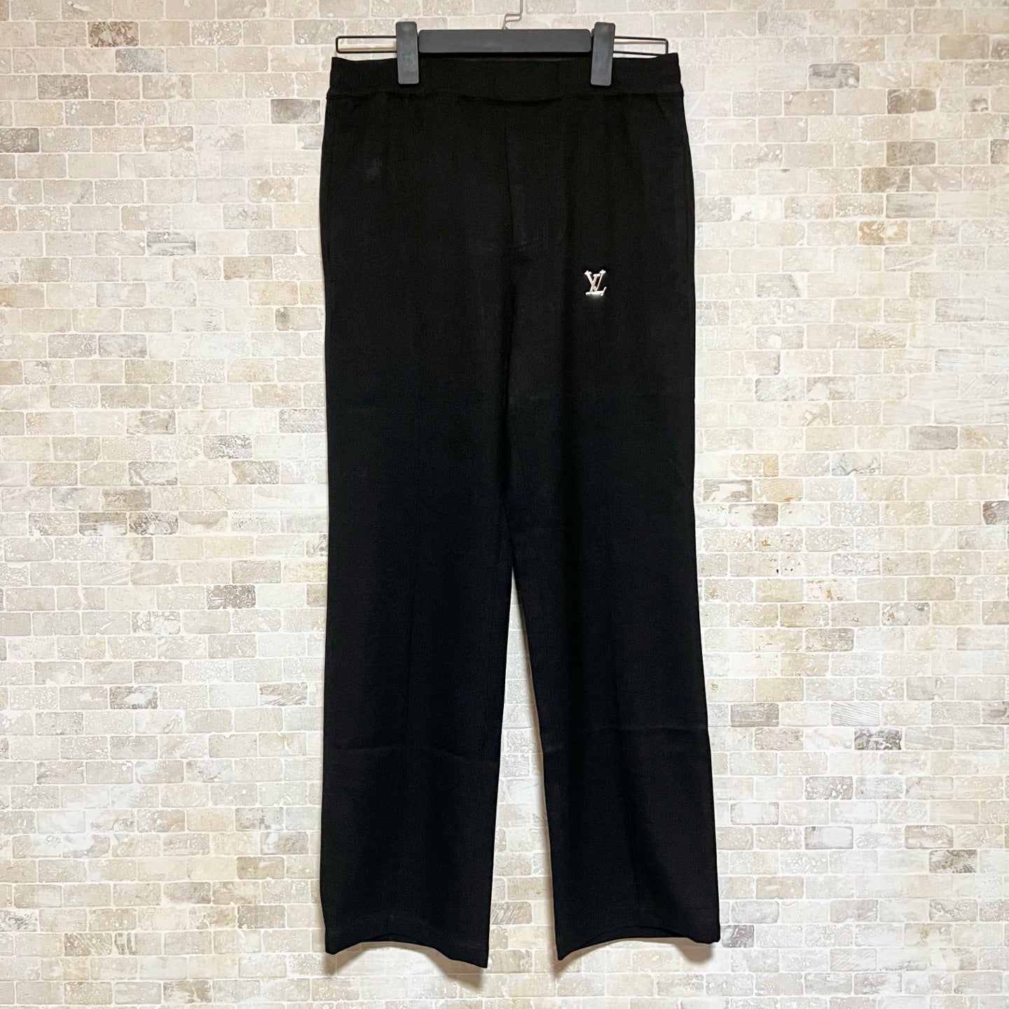 Black Louis Vuitton pants with belt loops and small gold LV logo at thigh