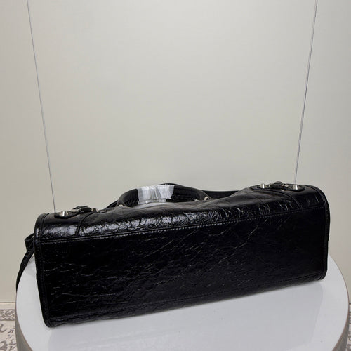 Black Balenciaga handbag side view with rolled handles and textured leather finish