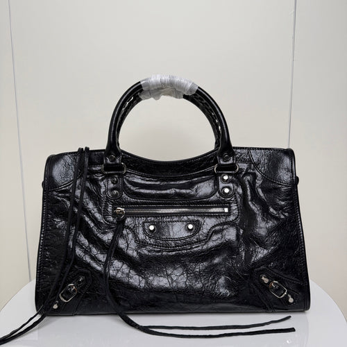 Black Balenciaga handbag with dual top handles, front zip pocket, and shoulder strap