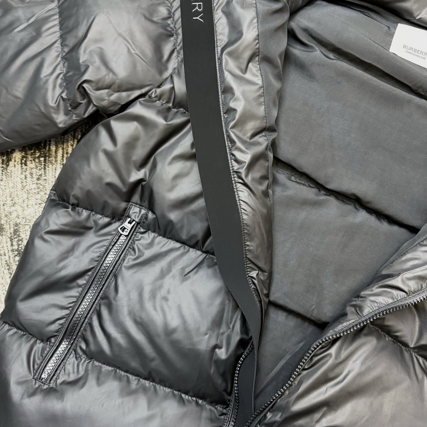 Dark puffer jacket front close-up with zip pocket and zipper pull
