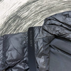 Dark puffer jacket shoulder panel with vertical Burberry logo tab