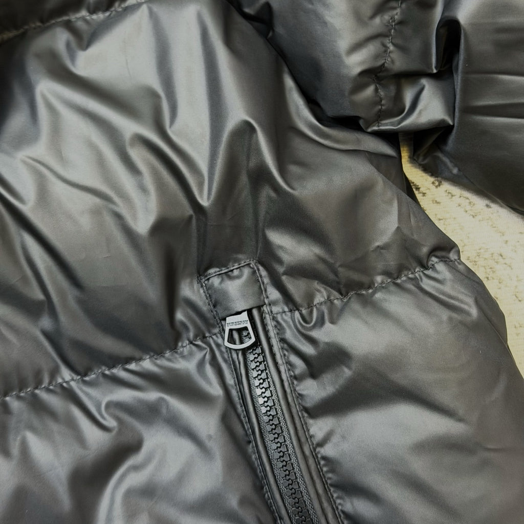 Dark puffer jacket sleeve and front zip pocket seam detail