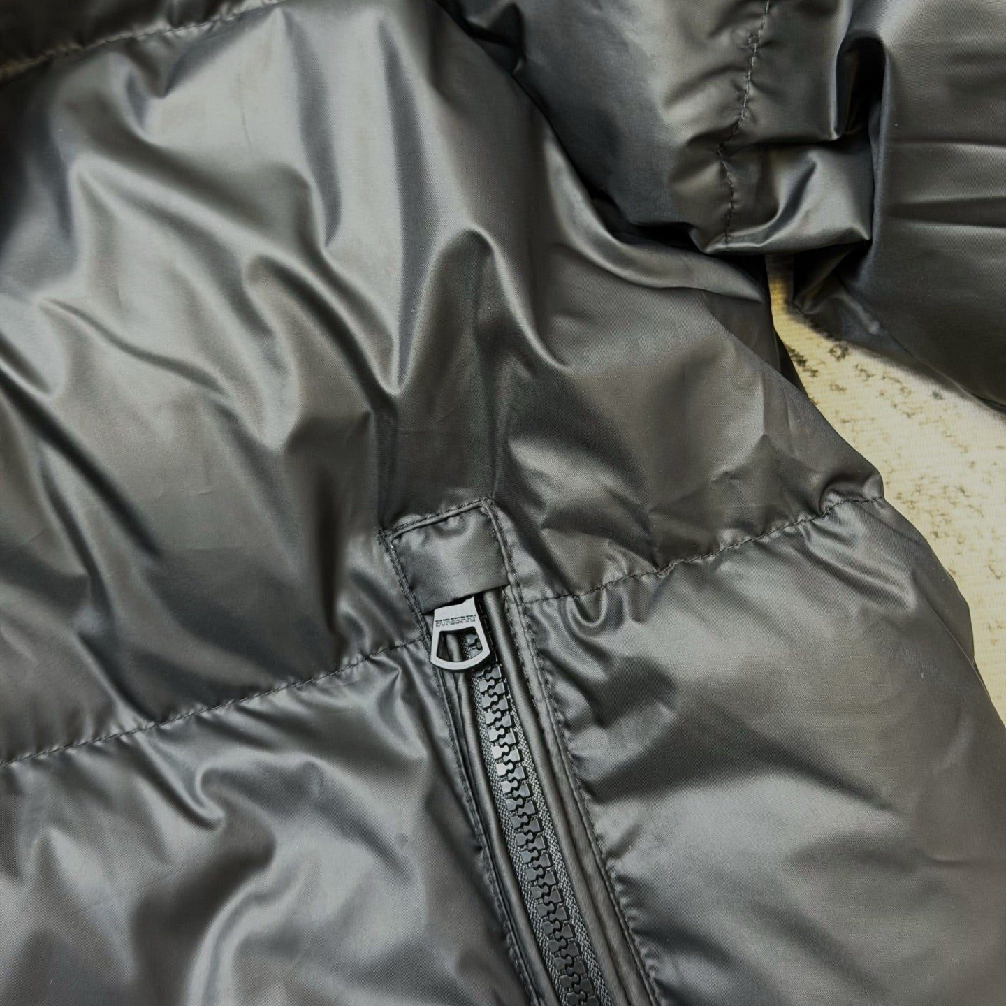 Dark puffer jacket sleeve and front zip pocket seam detail