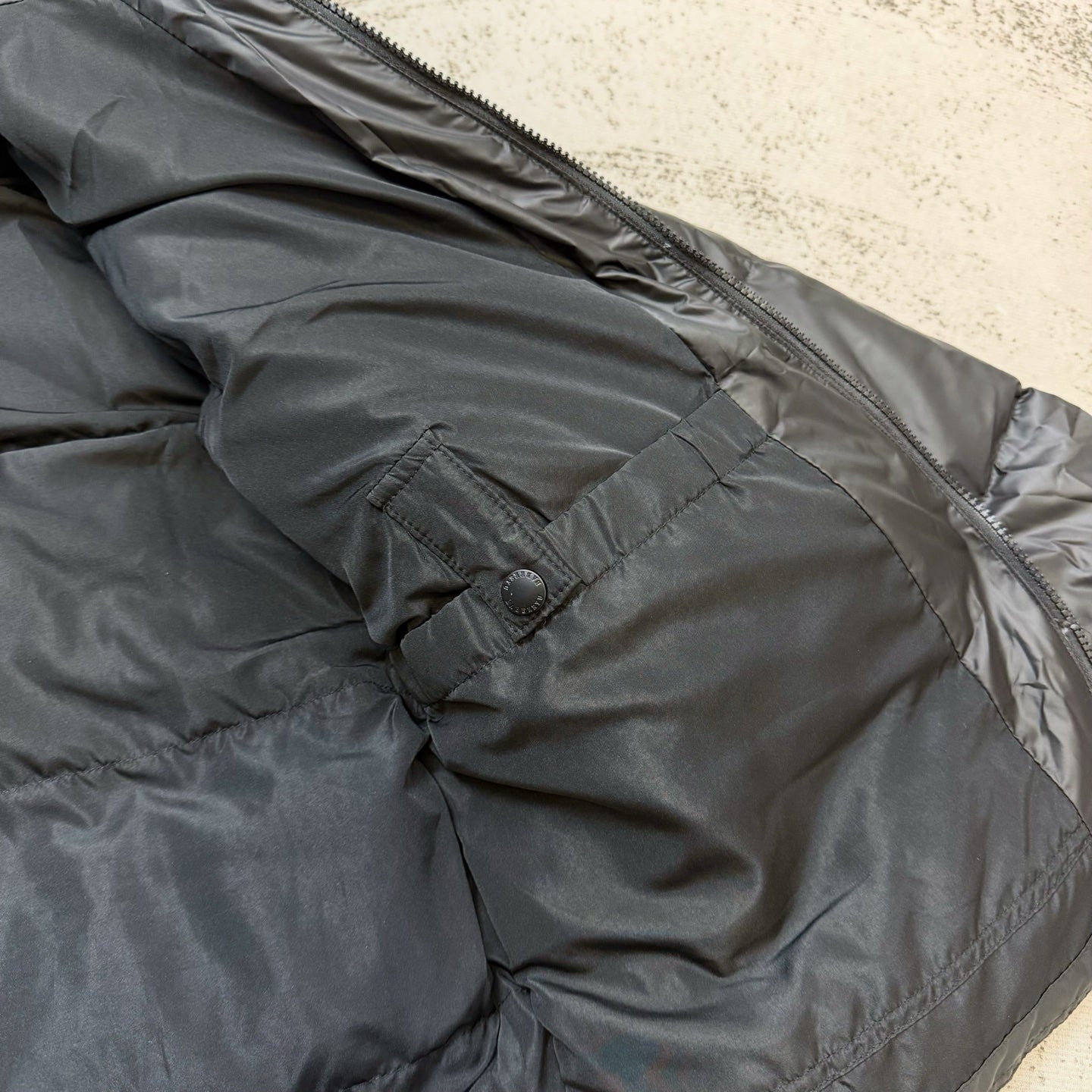 Dark puffer jacket back close-up with snap tab and seam stitching