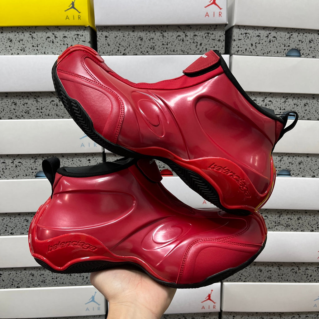 Pair of red glossy high-top sneakers with black trim, held for display
