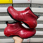 Pair of red glossy high-top sneakers with black trim, held for display