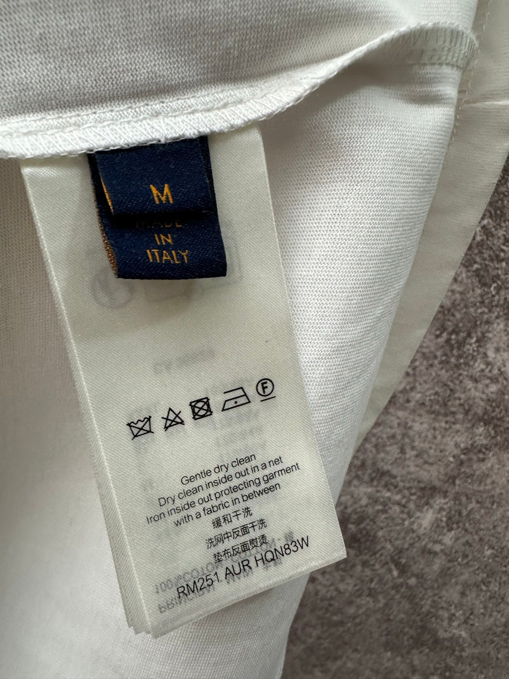Clothing care label tag inside long-sleeve shirt, size M, fabric and washing icons