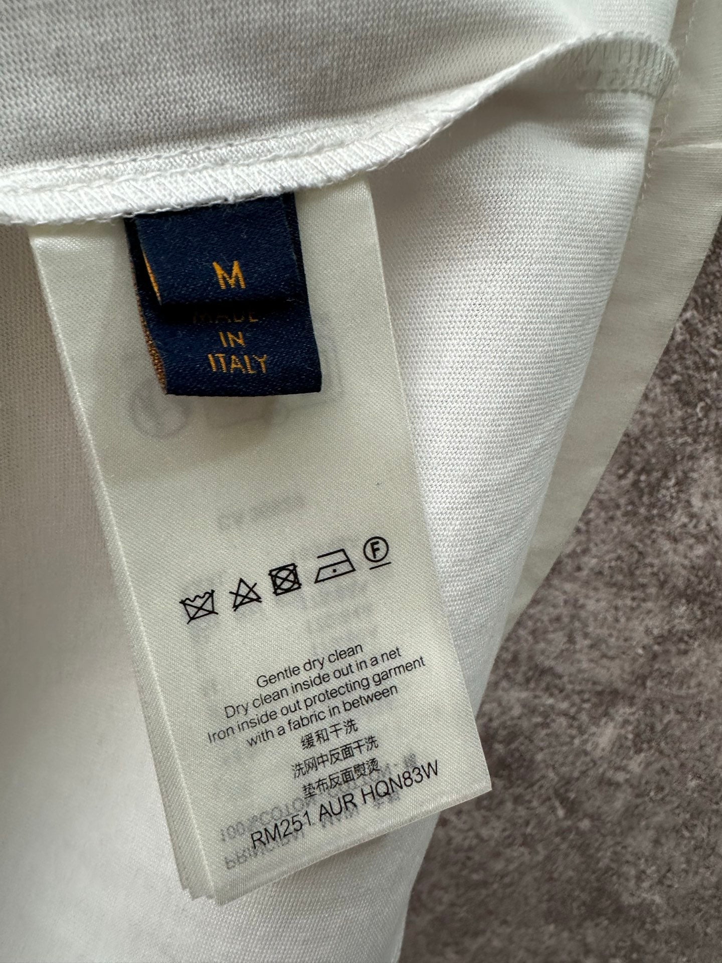Clothing care label tag inside long-sleeve shirt, size M, fabric and washing icons