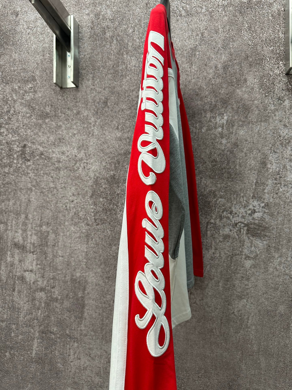 Long-sleeve raglan shirt viewed from side, with large red panel and white logo print