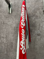 Long-sleeve raglan shirt viewed from side, with large red panel and white logo print