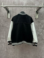 Back view of black long varsity jacket with white sleeve panels and ribbed hem