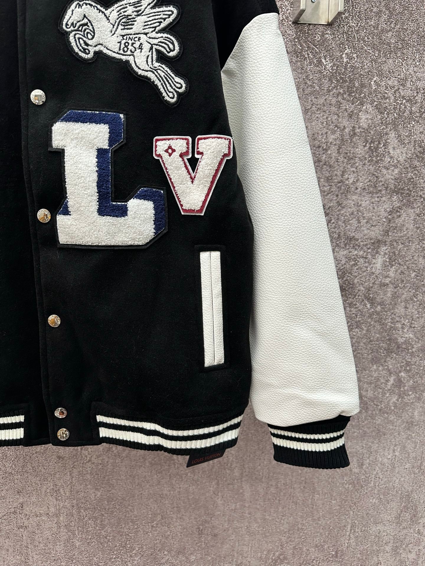 Black long varsity jacket with white sleeves and ribbed cuffs and hem