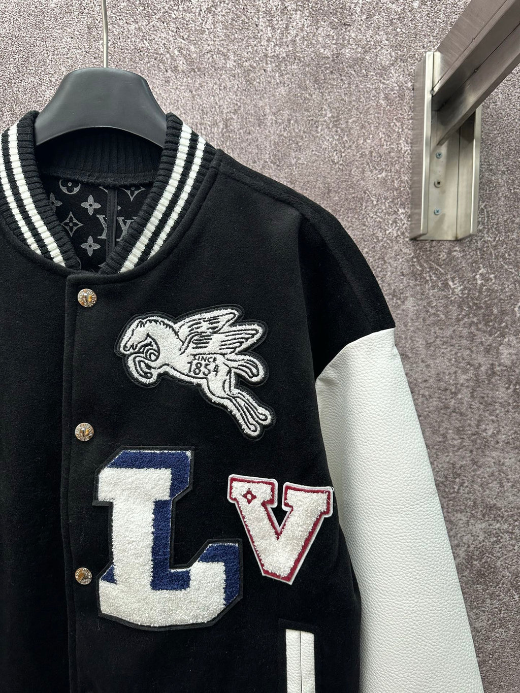 Black varsity jacket front detail with winged horse crest and LV letter patch