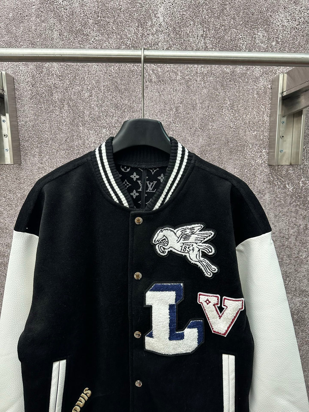 Black long varsity jacket with white sleeves, crest logo and LV letter patches on front
