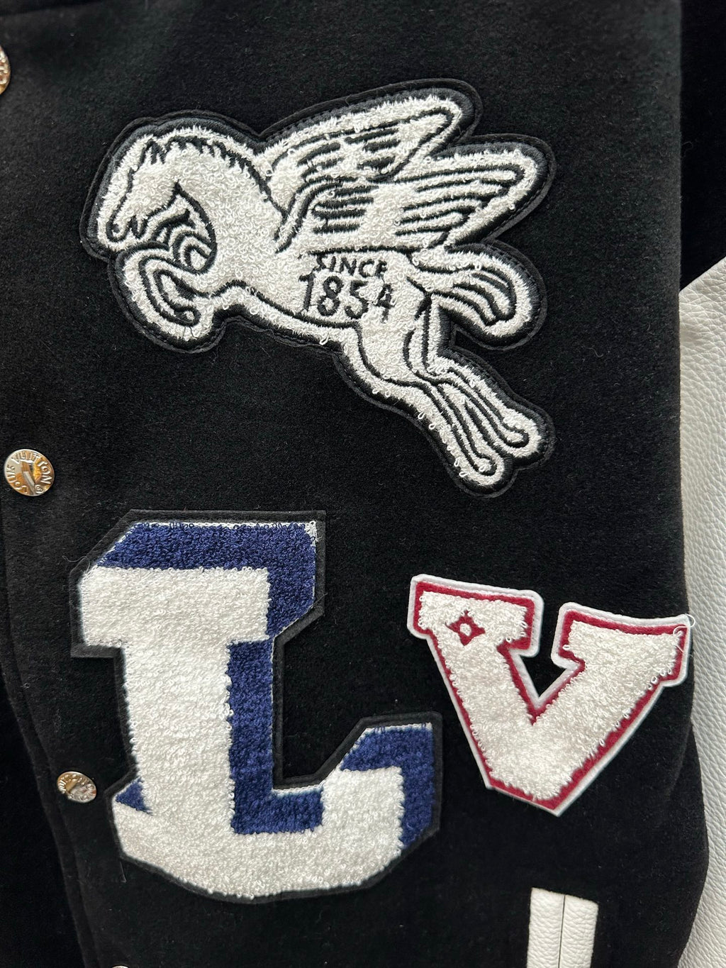 Embroidered winged horse and LV letter patches on black varsity jacket front