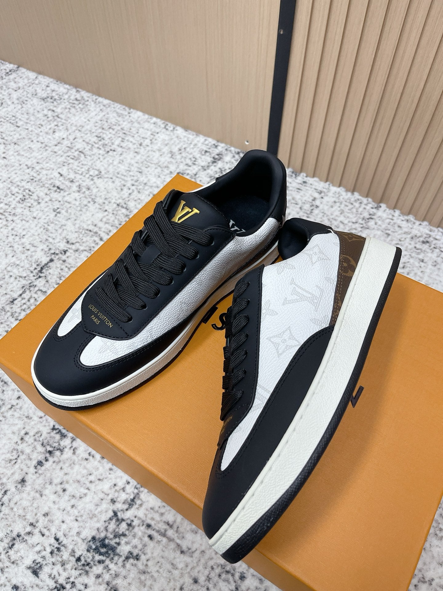 Louis Vuitton low-top sneakers with black uppers, white swoosh, gold LV on tongue