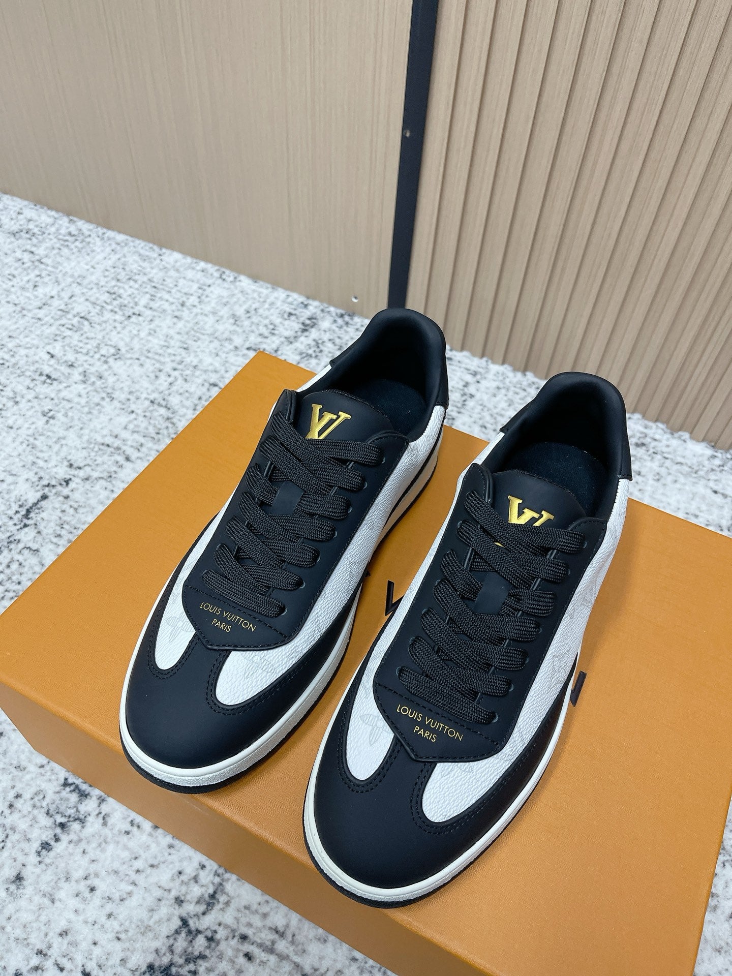 Louis Vuitton low-top sneakers with black uppers, white swoosh, gold LV accents