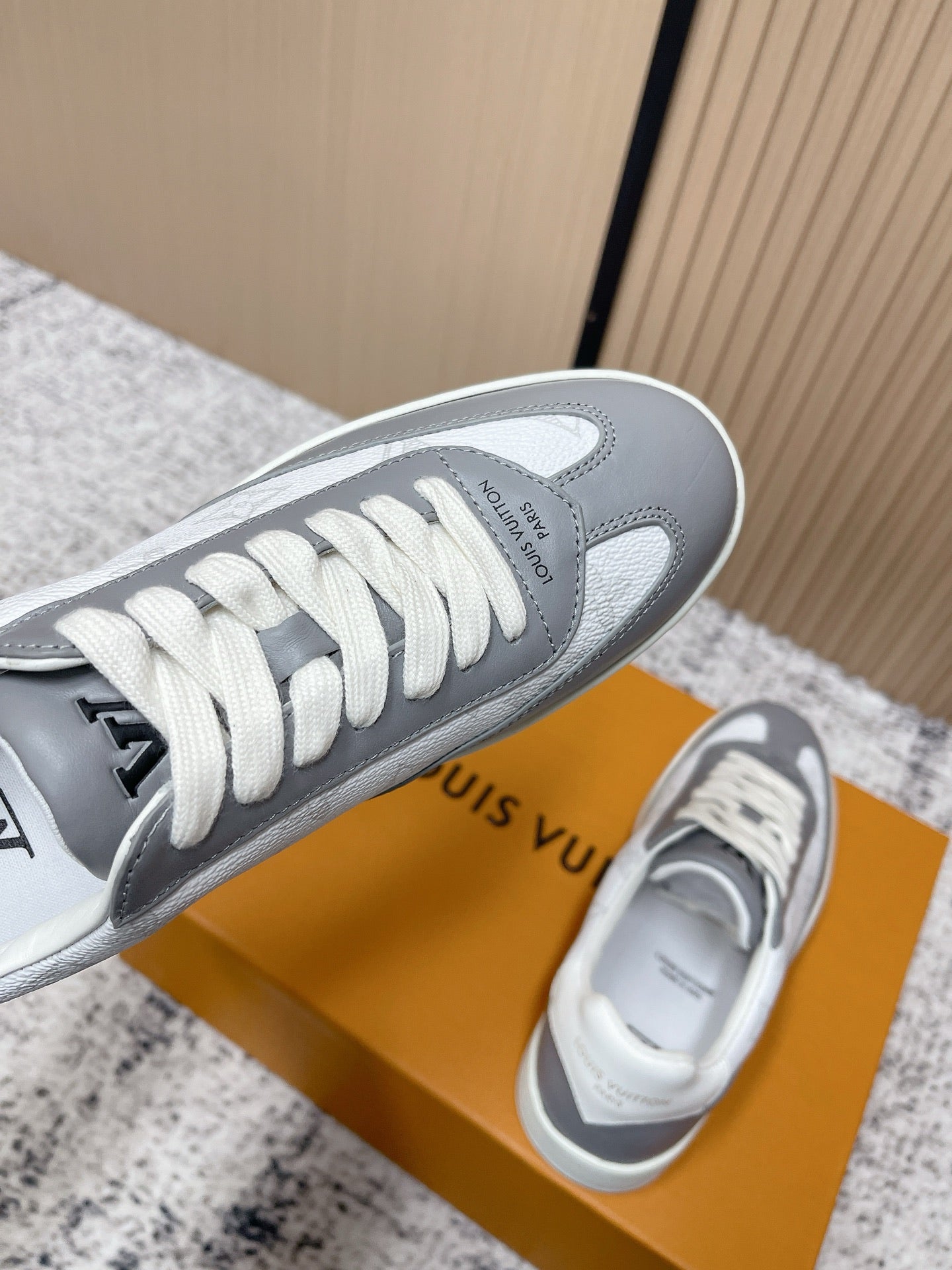 Low-top sneakers viewed from the toe, white laces on gray toe cap, side logo