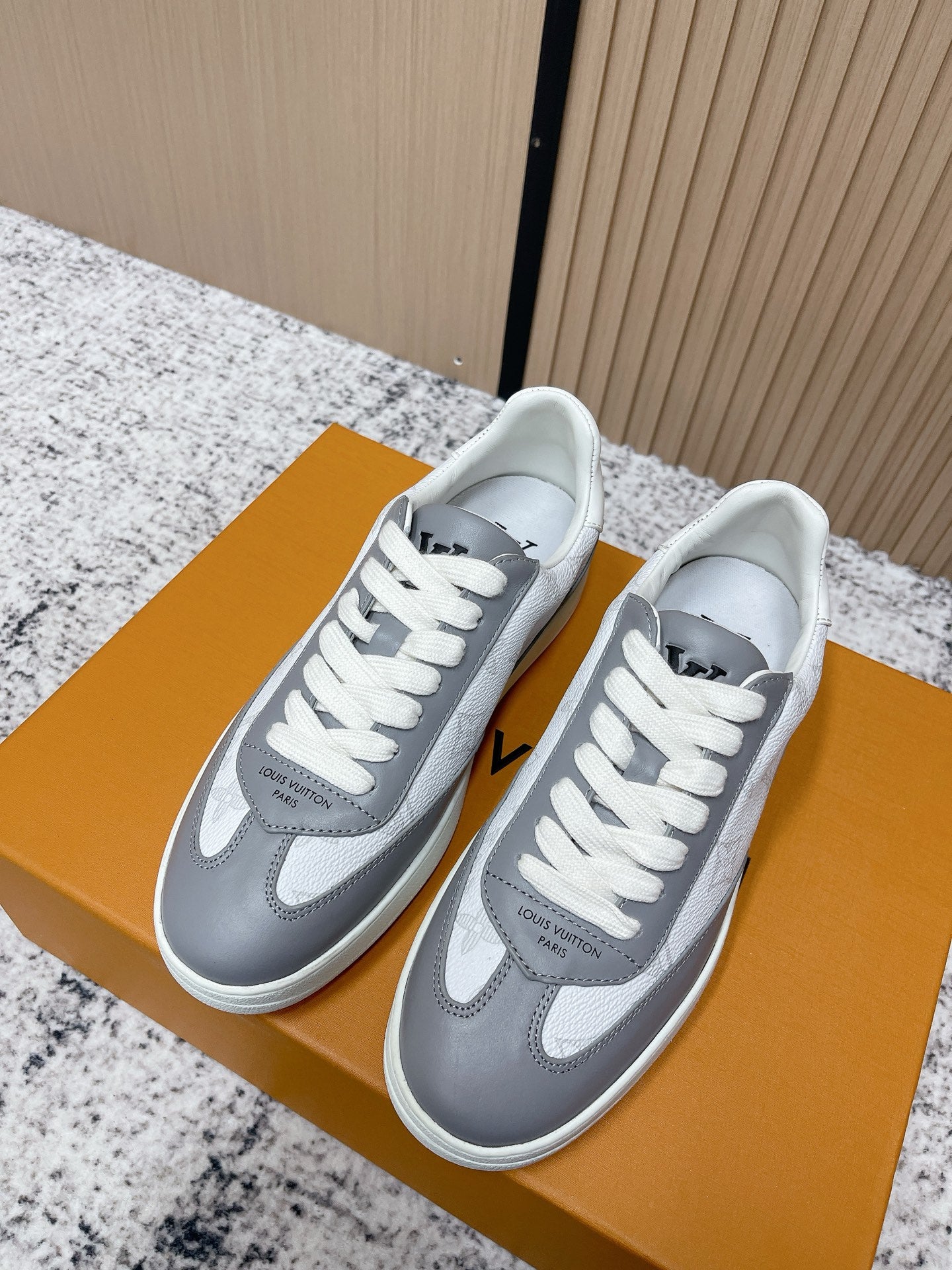 Low-top sneakers with white uppers and gray panels, white laces, side logos