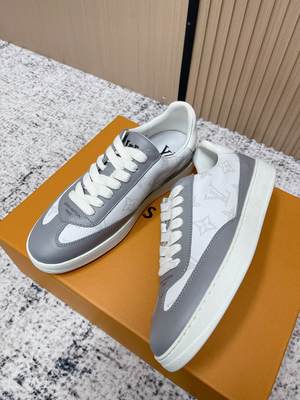 Low-top sneakers with white uppers, gray side panels, white laces, visible logo details