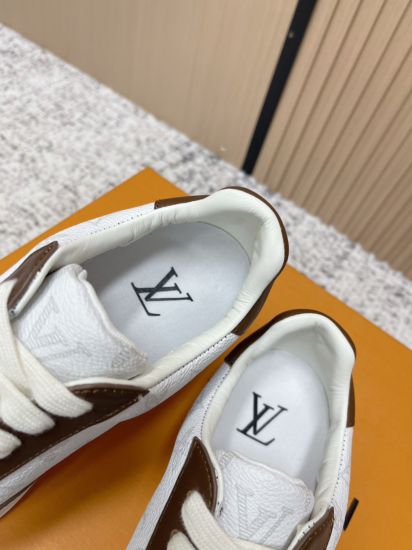 Brown-and-white sneakers with white insoles and LV logo on the footbeds