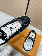 Black low-top sneakers with white laces and monogram-style print, toe-and-heel angle.