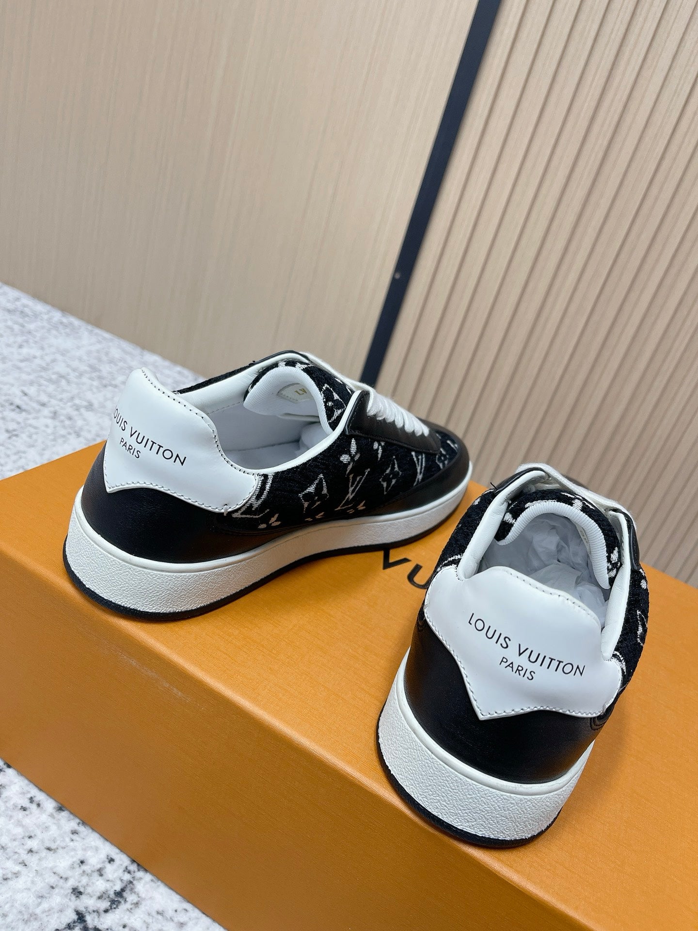 Black low-top sneakers with white heel tab and strap, lace-up profile on box.