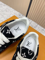 Black low-top sneakers with white interior lining and monogram pattern, close-up.