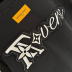 Black T-shirt detail with embroidered 'Lovers' logo graphic and star motif