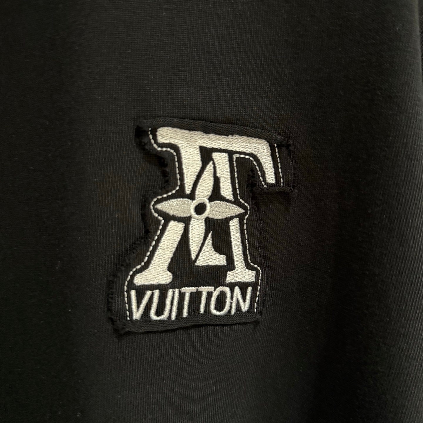 Black T-shirt with embroidered Louis Vuitton logo patch on chest