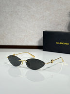 Balenciaga sunglasses with dark tinted lenses and gold-tone metal frame.