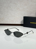Balenciaga sunglasses with dark lenses, gold-tone frame, and clear cutout arms.