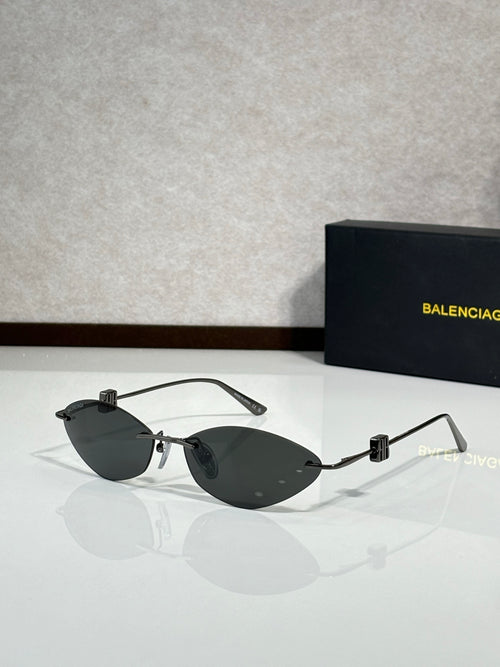 Balenciaga sunglasses with dark lenses, gold-tone frame, and clear cutout arms.