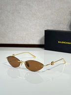 Balenciaga sunglasses with warm brown tinted lenses and gold-tone metal frame.