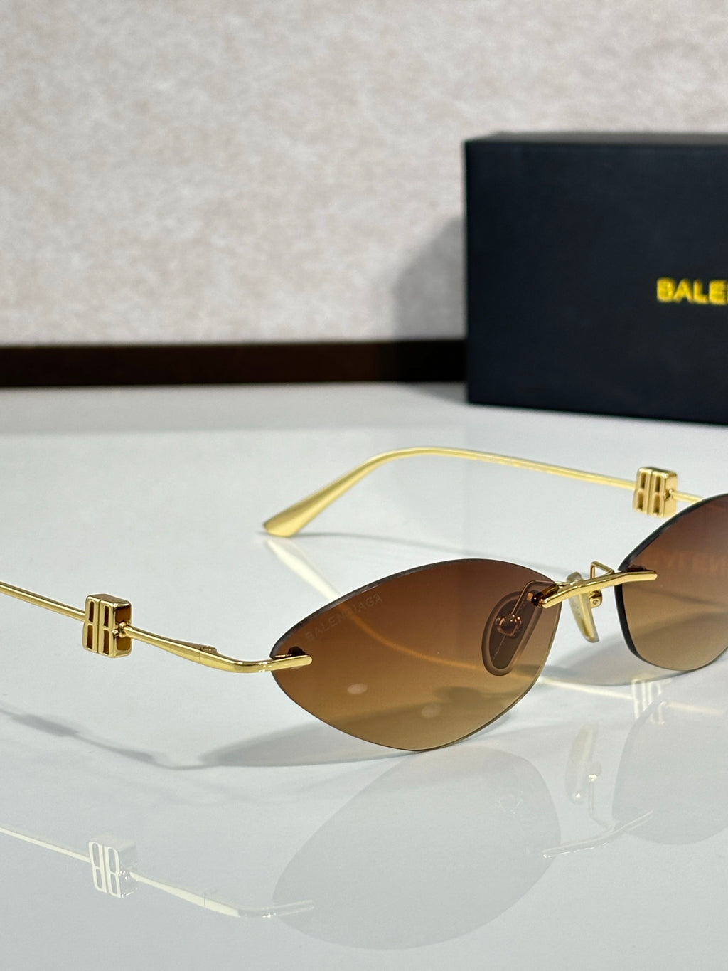 Balenciaga sunglasses close-up with brown lenses and gold-tone hinge details.