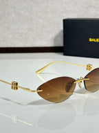 Balenciaga sunglasses close-up with brown lenses and gold-tone hinge details.