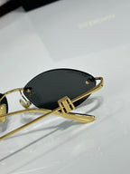 Balenciaga sunglasses close-up with dark lenses and gold-tone metal arms.