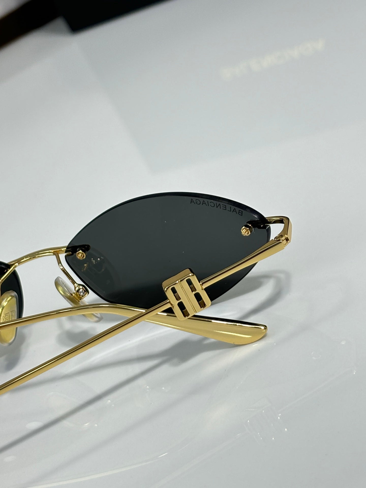 Balenciaga sunglasses close-up with dark lenses and gold-tone metal arms.