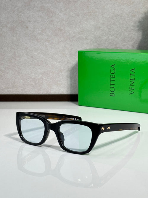 Black square sunglasses with dark lenses and gold crown detail at the temple