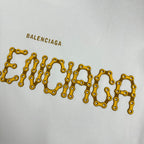 Close-up of gold Balenciaga lettering on a white sweatshirt front