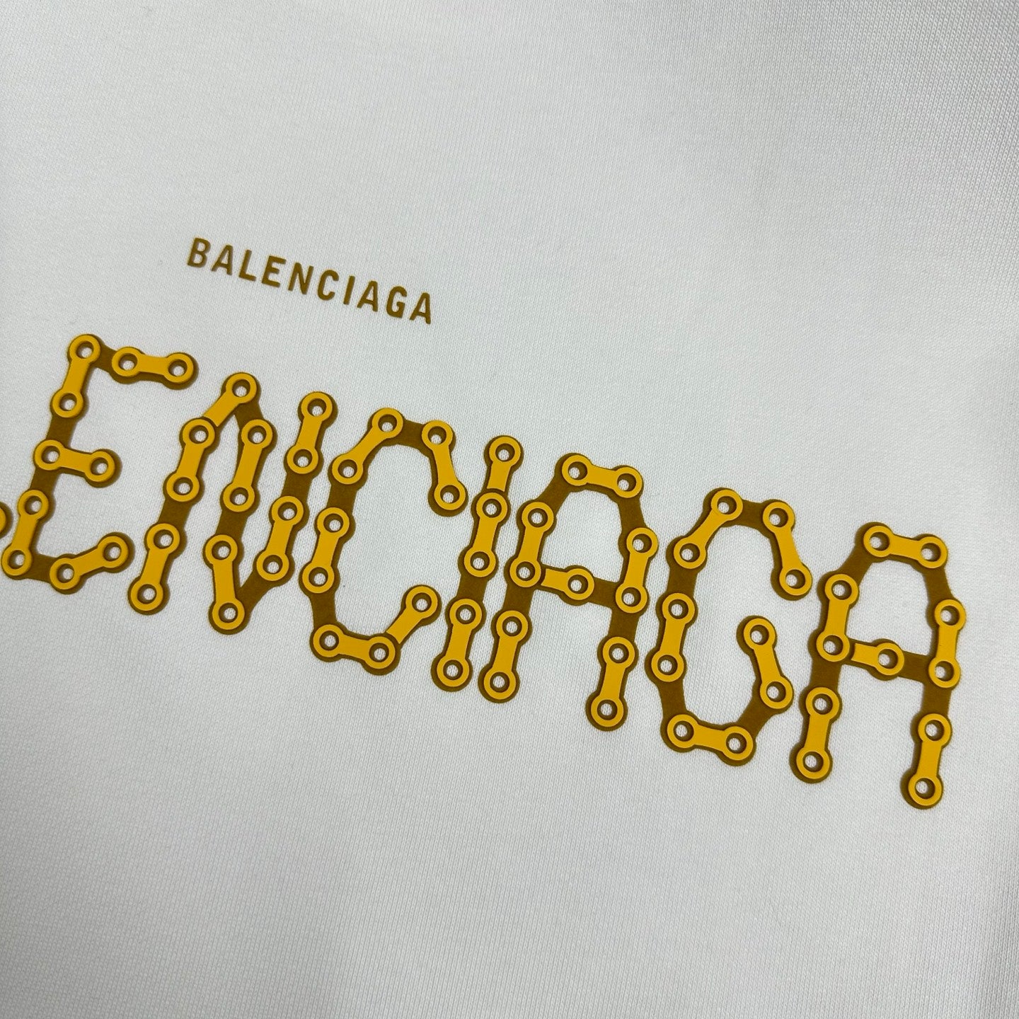 Close-up of gold Balenciaga lettering on a white sweatshirt front