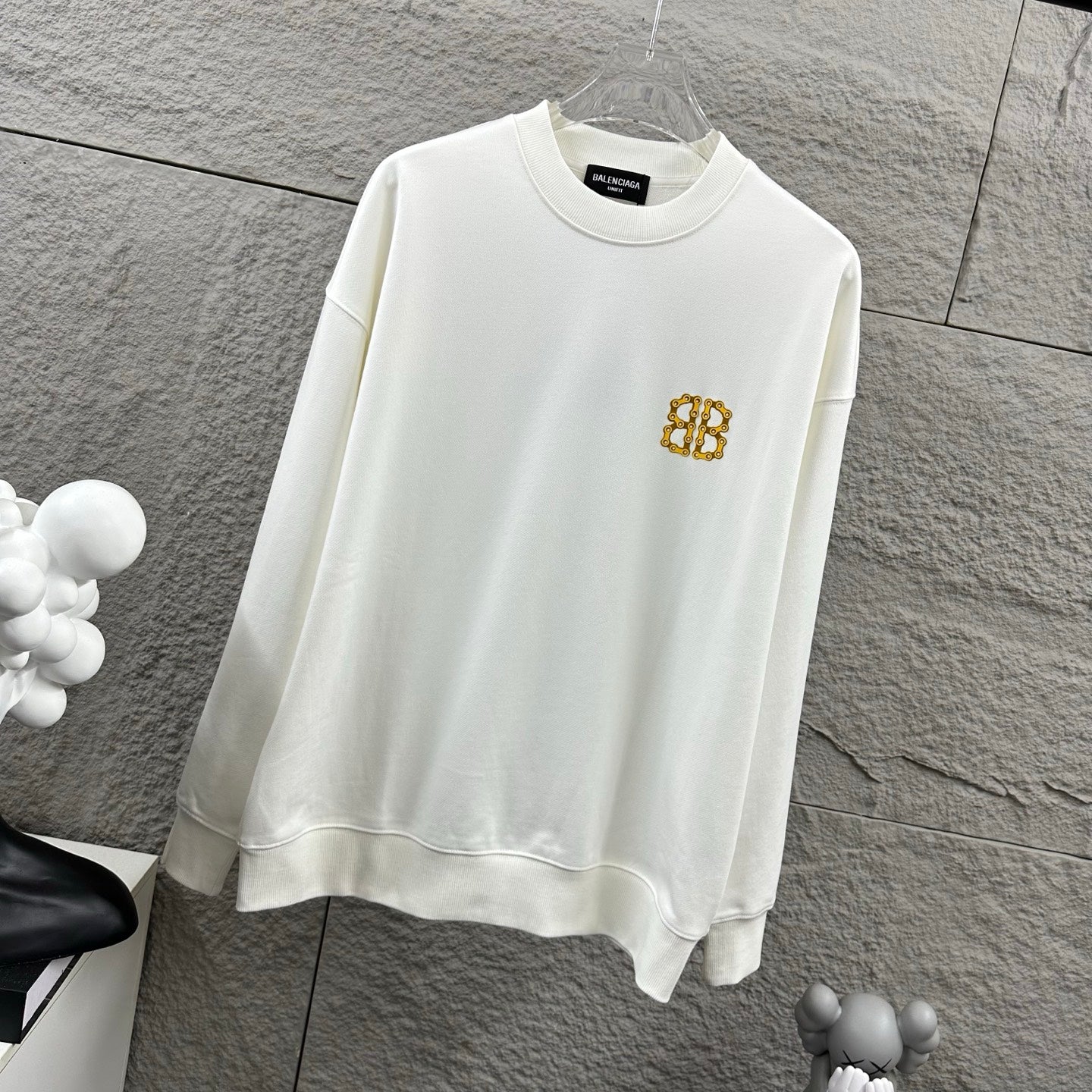 White crew-neck sweatshirt with gold monogram logo on the chest