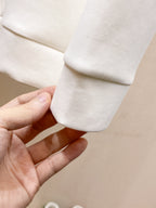 White crewneck sweatshirt cuff with hand holding sleeve hem seam.