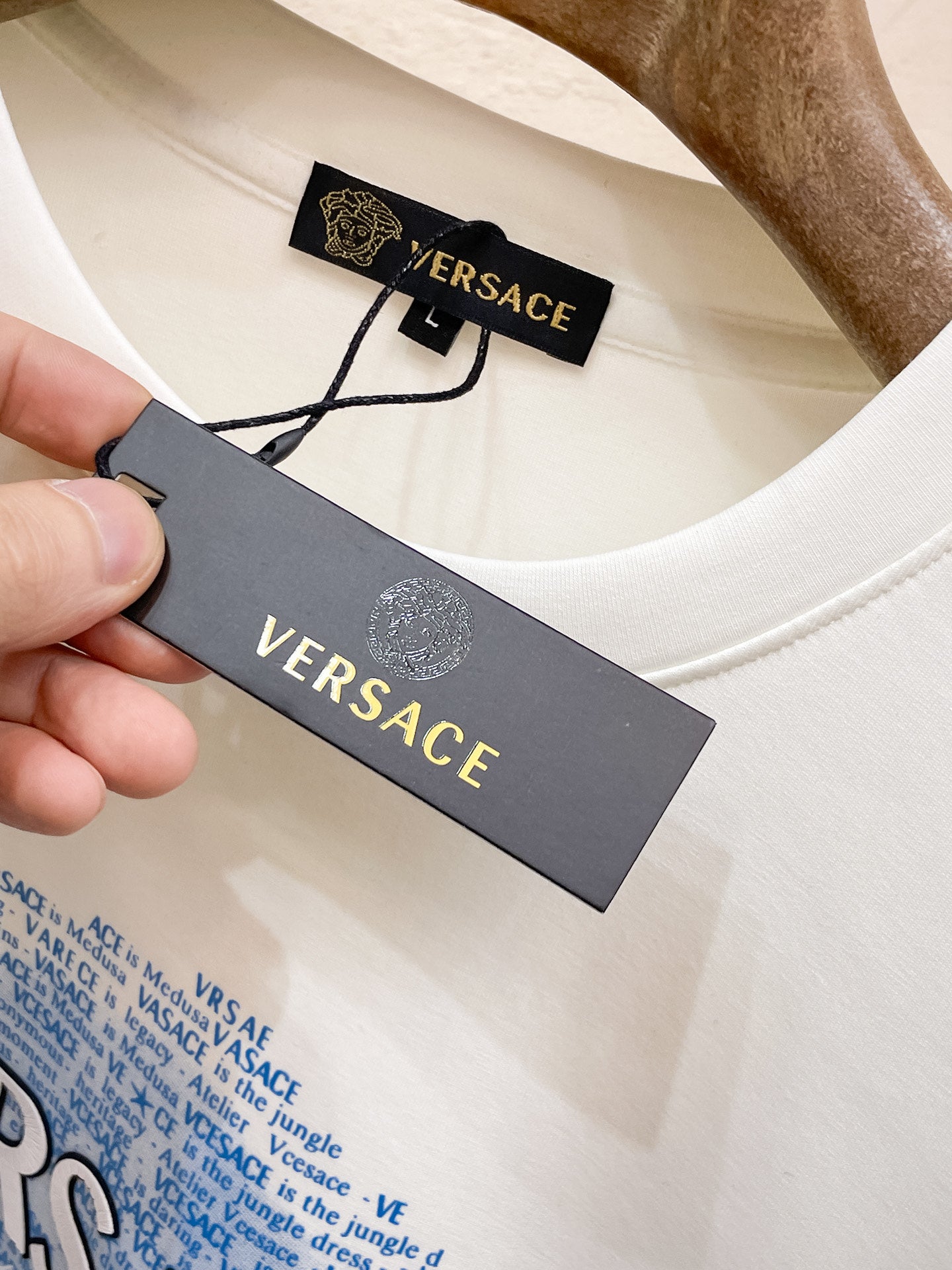 White crewneck sweatshirt with attached Versace clothing tag and care label.